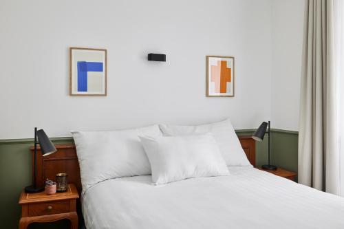 a bedroom with a white bed with two pictures on the wall at Base Lausanne in Lausanne