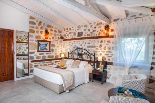 a bedroom with a white bed and a stone wall at Acrotel Athena Residence in Elia