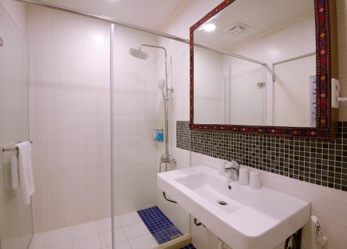 ein Bad mit einem Waschbecken und einer Dusche mit einem Spiegel in der Unterkunft Mixa Hostel in Hualien