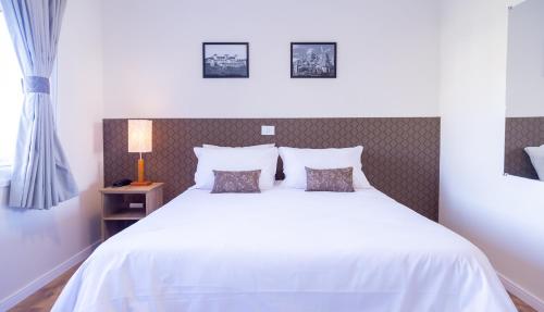 a bedroom with a large white bed with two pillows at Village de Charme - 2km do Capivari in Campos do Jordão