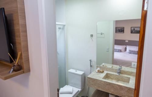 a bathroom with a sink and a toilet and a mirror at Village de Charme - 2km do Capivari in Campos do Jordão