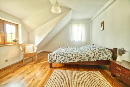 a bedroom with a bed and a chair at DOM POD STRZECHĄ NA KASZUBACH in Ostrowite