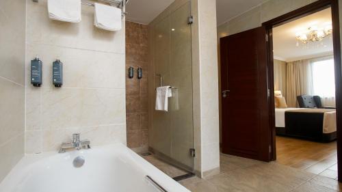 a bathroom with a bath tub and a shower at Sarova Woodlands Hotel and Spa in Nakuru