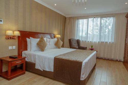 a hotel room with a large bed and a window at Sarova Woodlands Hotel and Spa in Nakuru