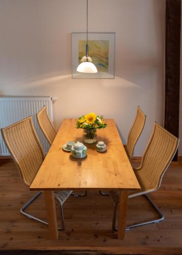 a wooden table with chairs and a vase of flowers on it at Historisches Fischerhäuschen in Ribnitz-Damgarten