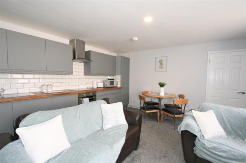 
a living room filled with furniture and a kitchen at Central Serviced Apartments by Roomsbooked in Cheltenham
