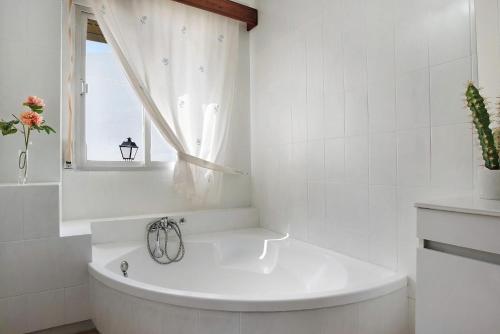 ein weißes Badezimmer mit Badewanne und Fenster in der Unterkunft Casa Pedro in Conil de la Frontera