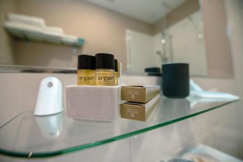 a glass counter with three bottles of hair products on it at Hotel Bruman Salerno in Salerno