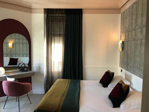 a bedroom with a bed and a desk and a chair at Le Grand Hôtel Mont Dore in Le Mont-Dore