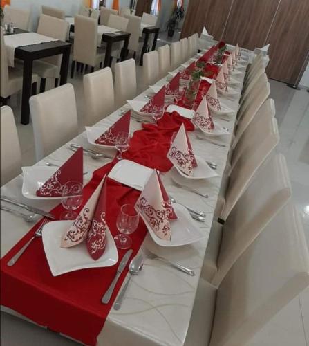 a long table with red and white plates and silverware at Jolán Pension & Restaurant in Číčov
