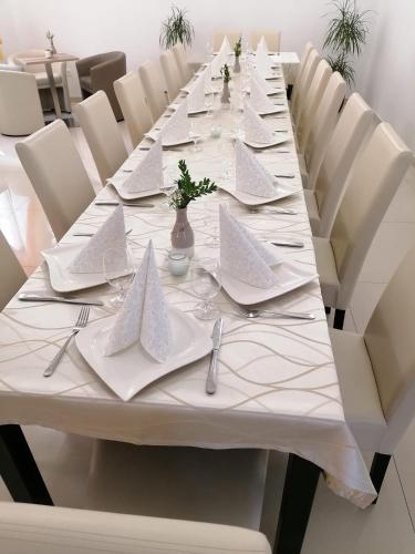 a long table with white plates and napkins on it at Jolán Pension & Restaurant in Číčov
