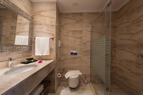 a bathroom with a toilet and a glass shower at Oz Hotels Sui in Alanya