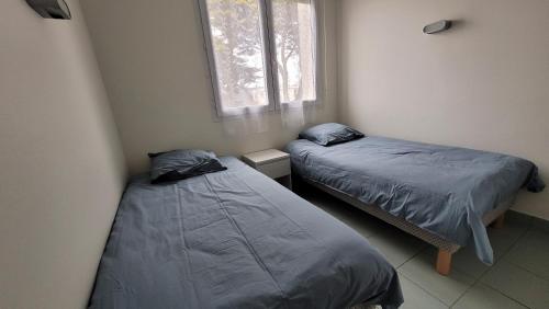 deux lits dans une petite pièce avec une fenêtre dans l'établissement T3 “Hoedic“- 50 m de la plage de Fort Bloqué/Ploemeur, à Ploemeur