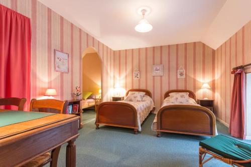 - 2 lits dans une chambre aux murs rayés roses dans l'établissement Le Caméléon, à Corgoloin