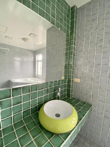 a green tiled bathroom with a sink and a mirror at 墾丁花見小院Villa包棟民宿 in Eluan
