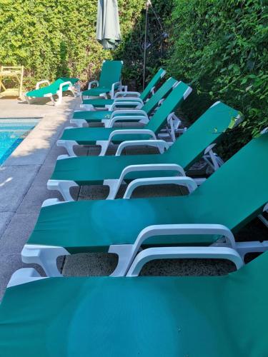a row of blue lounge chairs next to a swimming pool at Residencial Playa Lisa in Boadilla del Monte