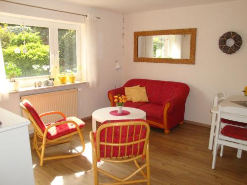 sala de estar con sofá rojo y sillas en Ferienwohnung in zentraler ruhiger Lage Klatt in Kappeln, en Kappeln