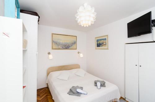 a white bedroom with a bed and a tv at White Wave Guest House in Dubrovnik