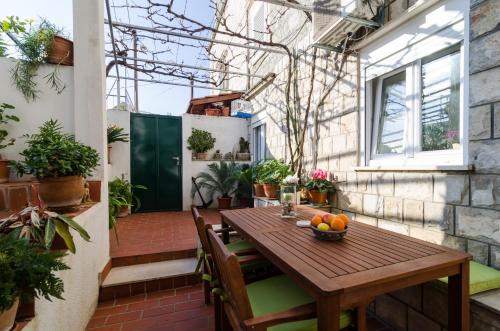 un patio al aire libre con mesa de madera y sillas en White Wave Guest House, en Dubrovnik