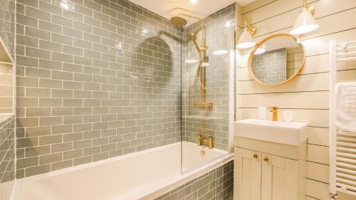 W łazience znajduje się wanna, umywalka i lustro. w obiekcie The Roman Apartment w mieście Hexham
