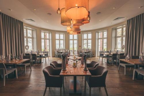 uma sala de jantar com mesas, cadeiras e janelas em Hotel Strandleben em Schleswig