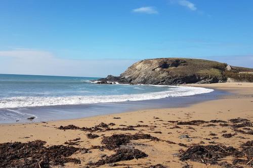 a beach with seaweed on the sand and the ocean at Captain's Cabin in Cadgwith