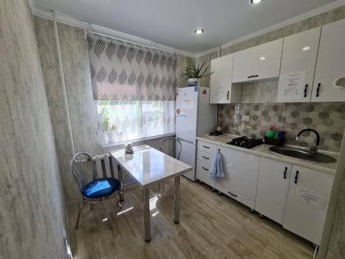 La cuisine est équipée d'une table, d'un évier et d'un réfrigérateur. dans l'établissement Посуточная квартира на Кердери с Wi-Fi, à Uralsk