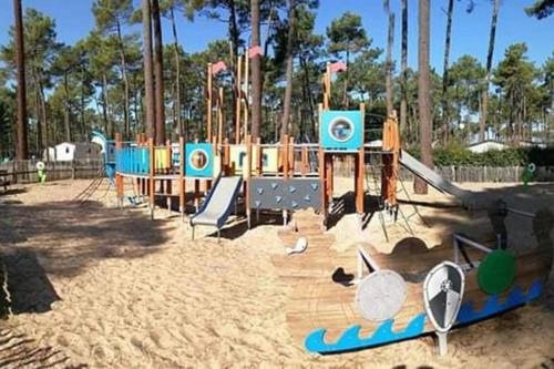 a playground with a slide and surfboards in the sand at Mobil home Rainbow, camping les dunes de contis in Saint-Julien-en-Born