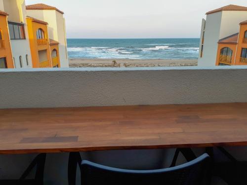 a table and a view of the ocean from a balcony at Superbe appartement vu mer avec parking et Wifi in Le Barcarès