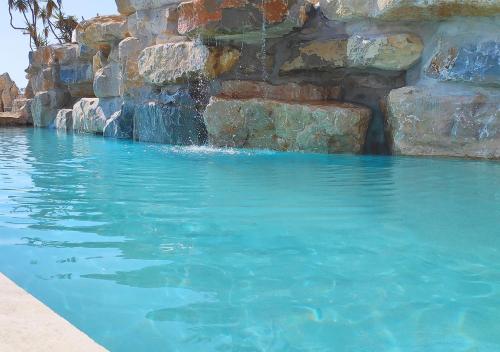 a swimming pool with blue water and a rock wall at Villa Occitana in Calvisson