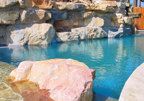 a swimming pool with rocks and blue water at Villa Occitana in Calvisson