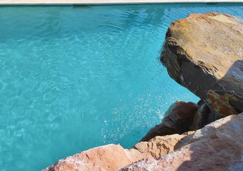 a pool of blue water next to some rocks at Villa Occitana in Calvisson