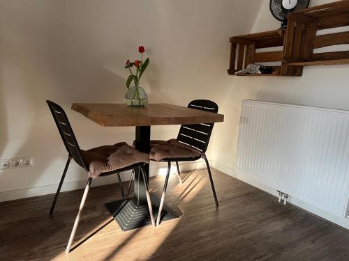 a table with two chairs and a vase with flowers on it at Mid83 in Woudsend