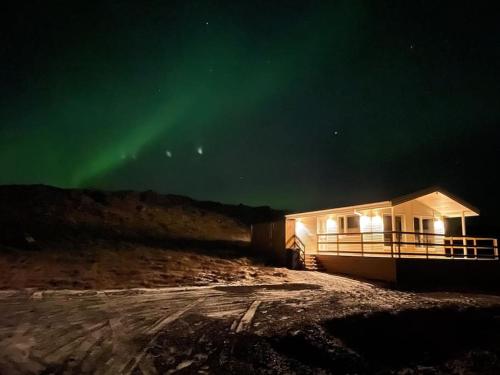 una cabaña con la aurora en el cielo por la noche en EYVÍK Cottages - Private HOT TUB!, en Selfoss