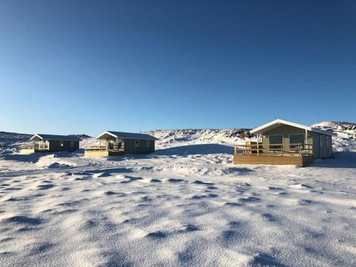 a group of huts in the snow at EYVÍK Cottages - Private HOT TUB! in Selfoss