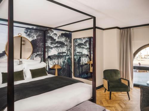 une chambre avec un lit à baldaquin et une chaise dans l'établissement Maisons du Monde Hôtel & Suites - Marseille Vieux Port, à Marseille