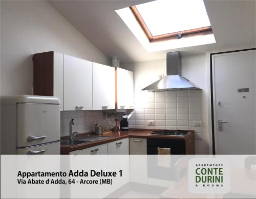 a kitchen with white cabinets and a sink and a refrigerator at Conte Durini Apartments & Rooms in Arcore