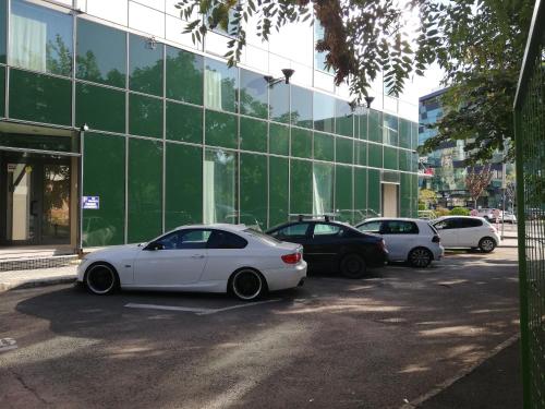 a white car parked in a parking lot in front of a building at Hotel CH Bucharest in Bucharest