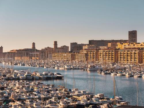 un port rempli de nombreux bateaux dans une ville dans l'établissement Maisons du Monde Hôtel & Suites - Marseille Vieux Port, à Marseille