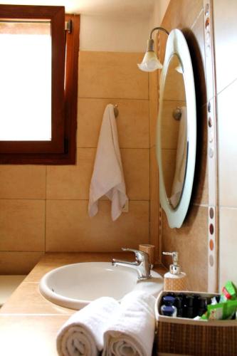 a bathroom with a sink and a mirror and towels at Villa Tenedos in Skopelos Town
