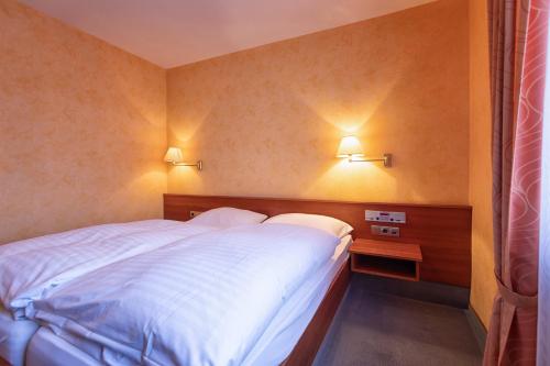 a bedroom with a bed and two lights on the wall at Hotel-Restaurant Weinhaus Grebel in Koblenz