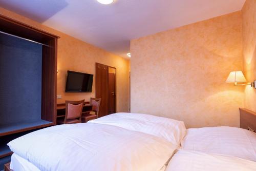 a hotel room with two white beds and a desk at Hotel-Restaurant Weinhaus Grebel in Koblenz
