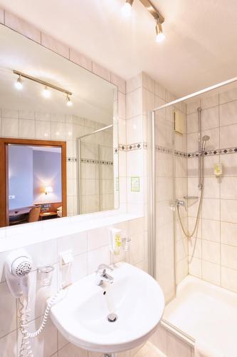 a bathroom with a sink and a shower and a mirror at Hotel-Restaurant Weinhaus Grebel in Koblenz