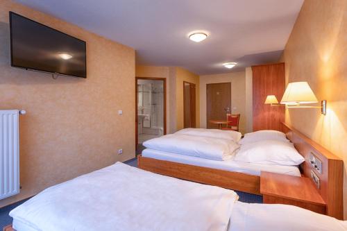 a hotel room with two beds and a flat screen tv at Hotel-Restaurant Weinhaus Grebel in Koblenz