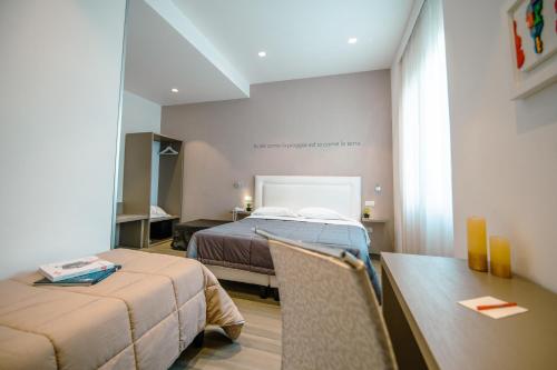 a room with two beds and a table and a desk at Hotel Bruman Salerno in Salerno