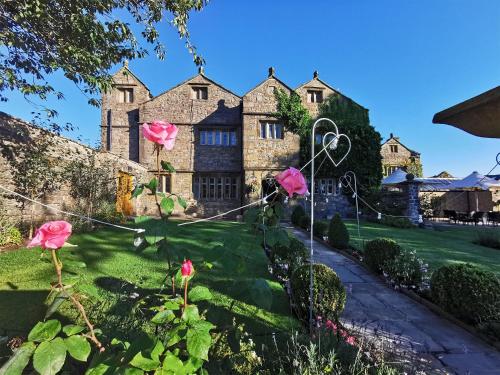 an old stone house with pink roses in the yard at Stirk House Hotel in Clitheroe