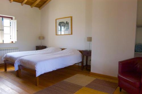 a bedroom with a white bed and a red chair at Quinta da Saimeira in Marvão