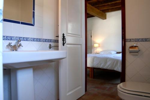 a bathroom with a sink and a toilet and a bed at Quinta da Saimeira in Marvão