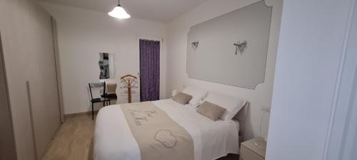 una camera da letto bianca con un letto con lenzuola e cuscini bianchi di Appartamento Belvedere 4 a Stresa