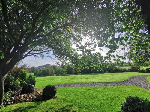 a green lawn with a tree and a path at Stirk House Hotel in Clitheroe